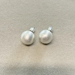 Primer plano de pendientes de bola de plata cepillada con detalle de textura mate