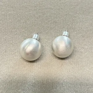 Primer plano de pendientes de bola en plata cepillada con un acabado mate suave.