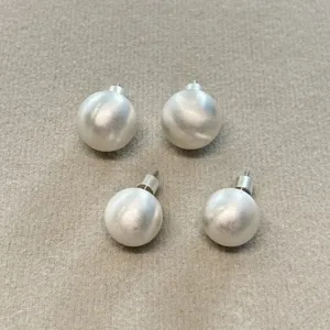Primer plano de cuatro bolas de plata cepillada para joyería sobre fieltro beige.