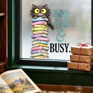 Detail view of a whimsical cat on a stack of books window decal with Booked & Busy text