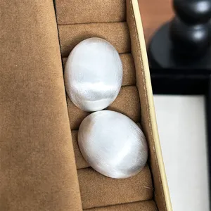 Vue détaillée de boucles d'oreilles ovales minimalistes en argent brossé et mat