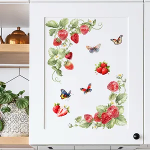 Aquarel muurstickers met aardbeien en vlinders aangebracht op een witte kastdeur.