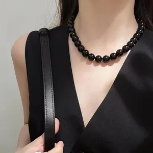 Close-up detail of a minimalist black bead strand necklace worn by a model as a choker