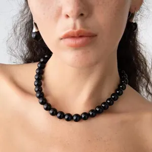 Detail view of elegant black beaded necklace and matching earrings worn by a model