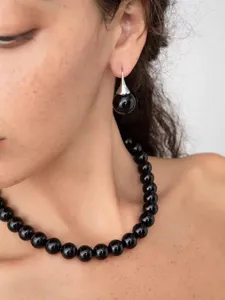 Close-up of elegant black bead necklace and matching teardrop earring on a model