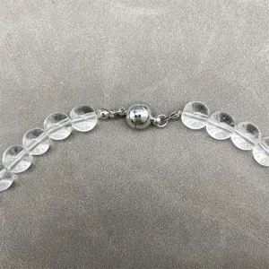 Detailed macro view of clear crystal beads and a polished silver magnetic necklace clasp.