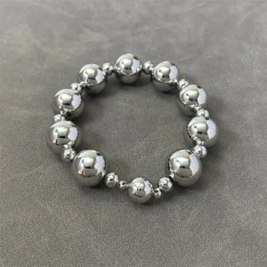 Close-up of metallic silver beaded necklace with magnetic clasp on grey background.