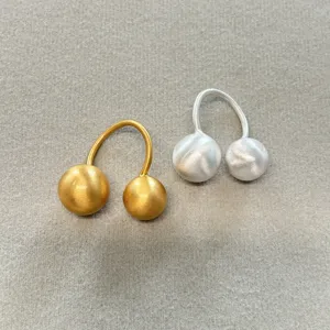 Primer plano de anillos en forma de U mate dorados y plateados con esferas de metal cepillado.