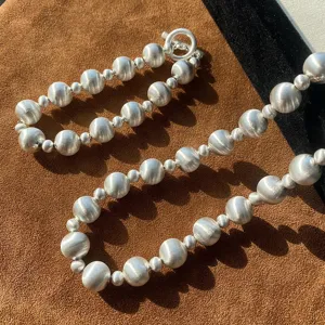 Vista detallada del collar y la pulsera de cuentas de plata cepillada con acabado mate