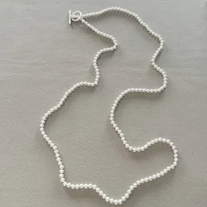 Primer plano de un collar largo con cuentas en plata mate y un elegante cierre de tipo palanca