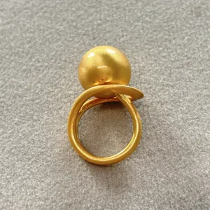 Vista detallada de un anillo de esfera minimalista en oro mate con textura cepillada