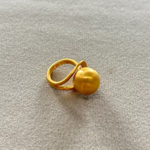 Vista macro detallada de un anillo con acabado en oro mate y una gran bola esférica