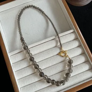 Detalle en primer plano de collar de cuentas de cuarzo ahumado con cierre dorado