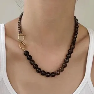 Detalle de primer plano de un collar de cuentas de cuarzo ahumado con cierre OT dorado fino