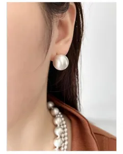 Primer plano de elegantes pendientes de esfera de plata cepillada y collar