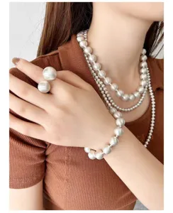 Primer plano de collares de cuentas de plata mate, pulsera y anillo en una modelo