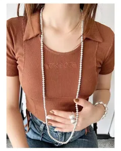 Detalle de collar largo de perlas con anillo y pulsera de plata cepillada para mujer.