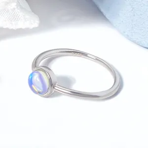 Macro detail of a minimalist S925 silver ring with an iridescent moonstone stone.
