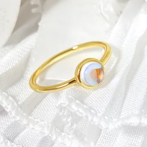 Close-up macro detail of a minimalist gold ring with a round iridescent moonstone inlay