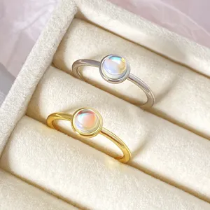 Detailed view of silver and gold plated oval moonstone rings in a velvet box