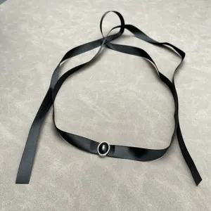 Detailed view of an elegant minimalist black ribbon choker with a black oval gemstone