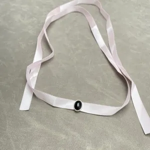 Close-up of niche design pink ribbon necklace with oval black stone centerpiece