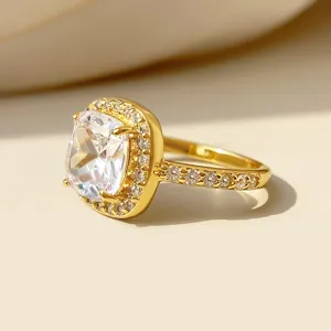 Macrodetail van luxe vergulde ring met cushion-cut zirkoonsteen en halo-zetting.