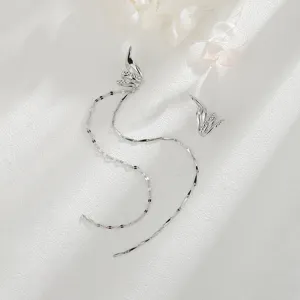 Λεπτομέρεια ασημένιου ear cuff με γεωμετρική αλυσίδα και μακριά φούντα σε λευκό