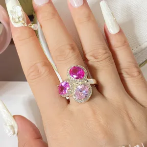Detailaufnahme eines luxuriösen Goldrings mit drei rosa ovalen Steinen und Kristall-Halo