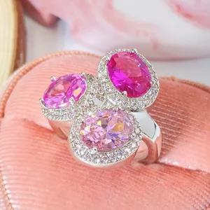 Makroaufnahme eines silbernen Rings mit drei ovalen rosa Steinen in einer Schatulle