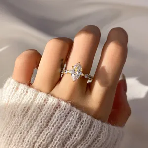 Close-up of gold marquise-cut cubic zirconia ring on a finger with knit sweater sleeve