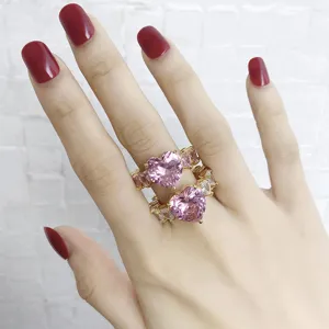 Nahaufnahme von rosafarbenen Herz-Zirkonia-Ringen mit Goldbeschichtung an der Hand