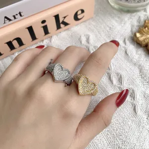 Detailansicht von herzförmigen Gold- und Silberringen mit Zirkonia-Besatz an der Hand