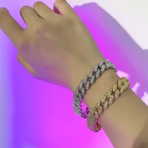 Close-up of gold and silver double-row iced out Cuban link bracelets on a person's wrist