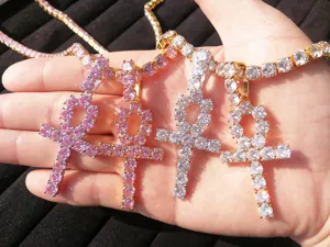 Dettaglio di ciondoli croce Ankh placcati oro con zirconi rosa e bianchi da 5mm in mano