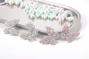 Makro-Detail von Zirkon-Schmetterlingsflügel-Anhängern mit rosa und weißen Steinen