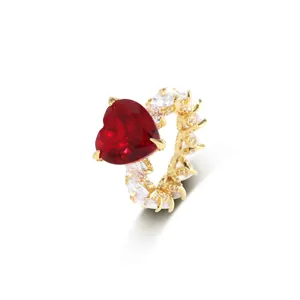 Detailopname van een vergulde ring met een grote rode hartvormige zirkonia steen