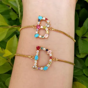Detailaufnahme von vergoldeten Kettenarmbändern mit bunten, mit Zirkon besetzten B und D Anhängern