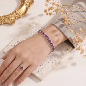 Dettaglio di un set di bracciale e anello in zircone viola su una mano elegante