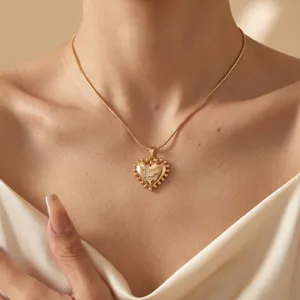Gold initial heart necklace with sparkling stone letter pendant and delicate bead border detail.