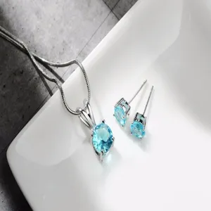 Primo piano dettagliato dell'elegante set di gioielli argentati con pietre rotonde azzurre.