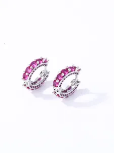 Primo piano di eleganti orecchini a cerchio in rame con pietre di zircone rosa