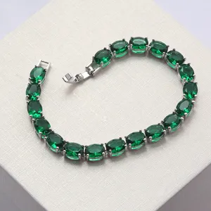 Nahaufnahme eines silberfarbenen Damenarmbands mit ovalen smaragdgrünen Kristallsteinen