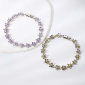 Primo piano di eleganti bracciali in rame con fiori in zirconia viola e verde.