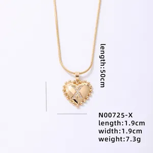Close-up of gold snake chain necklace featuring a crystal paved letter X heart pendant.
