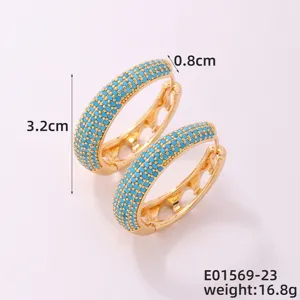 Detalle de pendientes de aro ovalados dorados con piedras azules y tamaño de 3,2 cm