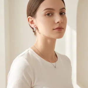 Close-up detail shot of elegant pave-set zircon hoop earrings and dainty chain necklace.