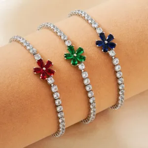 Detailed view of three flower tennis bracelets with red, green, and blue crystals