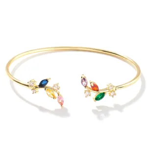 Dettaglio di bracciale rigido dorato a ramo di salice con pietre marquise multicolore