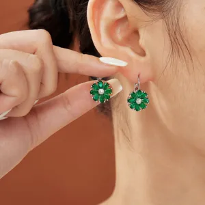Close-up detail of green gemstone flower earrings on model's ear